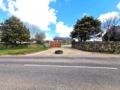 a road with a stone wall and a gate on the side at The Barn-family getaway - Nr Port Isaac in Port Isaac