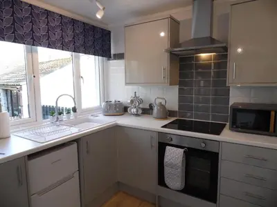 a kitchen with white cabinets and a stove top oven at Seaside Escape in St Ives