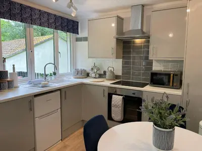 a kitchen with white cabinets and a table at Seaside Escape in St Ives
