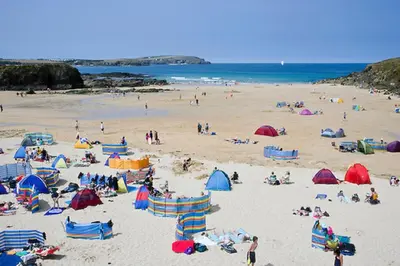 a group of people on a beach with umbrellas at Wendy Lodge- Chalet Cottage, Sleeps 6 Adults in Padstow