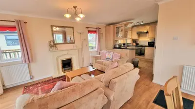 a living room with two couches and a fireplace at Wendy Lodge- Chalet Cottage, Sleeps 6 Adults in Padstow