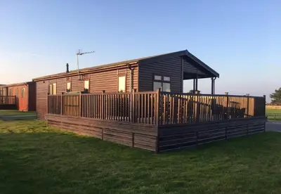 a large wooden cabin with a large deck at Wendy Lodge- Chalet Cottage, Sleeps 6 Adults in Padstow