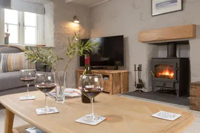 a living room with wine glasses on a table with a fireplace at Beach Cottage in St. Agnes