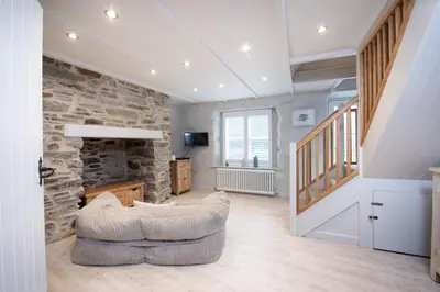 a living room with a couch and a stone wall at Beach Cottage in St. Agnes