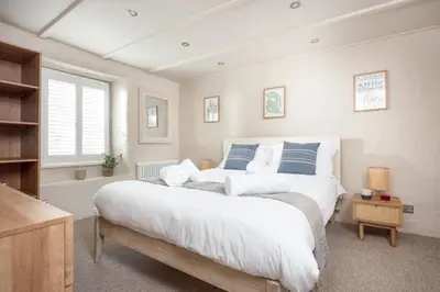 a bedroom with a large white bed with blue pillows at Beach Cottage in St. Agnes
