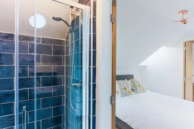 a bedroom with a blue tiled shower and a bed at Little Cedars House in Truro