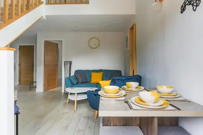 a living room with a table and a blue couch at Little Cedars House in Truro