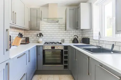 a kitchen with white cabinets and a stove top oven at Little Cedars House in Truro