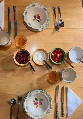 a wooden table with plates and forks and spoons at Charming Guest House in Cornish Countryside in Bodmin