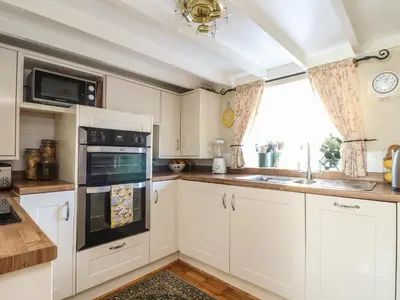 a kitchen with white cabinets and a window at The Nest in Helston
