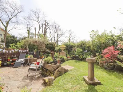 a backyard with a garden with a table and chairs at The Nest in Helston