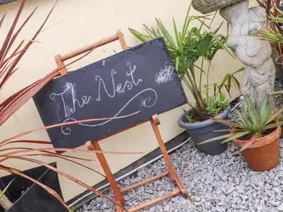 a chalkboard sign sitting next to some plants at The Nest in Helston