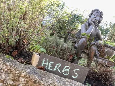 a statue of a girl sitting on a rock at The Nest in Helston