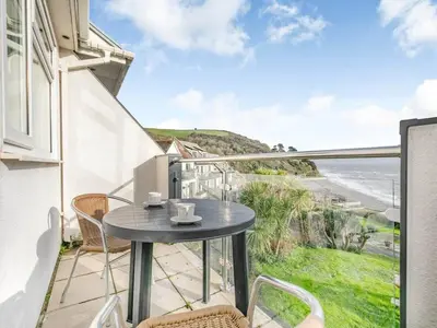 a table on a balcony with a view of the ocean at Beach View - Mount Brioni in Downderry