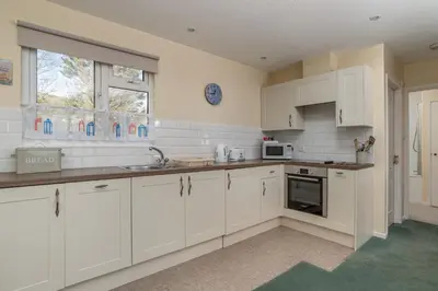 a kitchen with white cabinets and a sink and a window at Beach View - Mount Brioni in Downderry