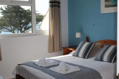 a bedroom with towels on a bed with a window at View of the Sea - Mount Brioni in Downderry