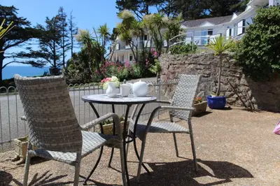 two chairs and a table with cups and mugs on it at Sandcastles - Mount Brioni in Downderry