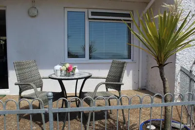 a patio table with two chairs and flowers on it at Sandcastles - Mount Brioni in Downderry