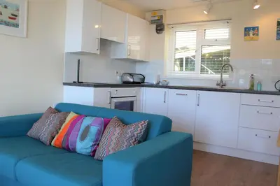 a living room with a blue couch in a kitchen at Sandcastles - Mount Brioni in Downderry