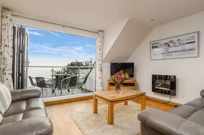 a living room with a table and a large window at Breakers - Mount Brioni in Downderry