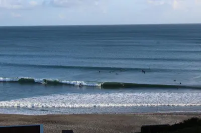 a group of people riding waves in the ocean at Apartment 2 - Mount Brioni in Downderry