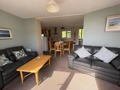 a living room with a leather couch and a table at Sunrise Bay - Mount Brioni in Downderry