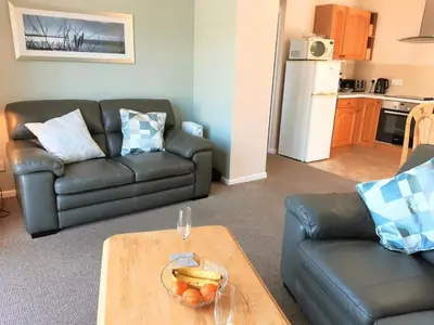 a living room with a couch and a table with a bowl of fruit at Sunrise Bay - Mount Brioni in Downderry