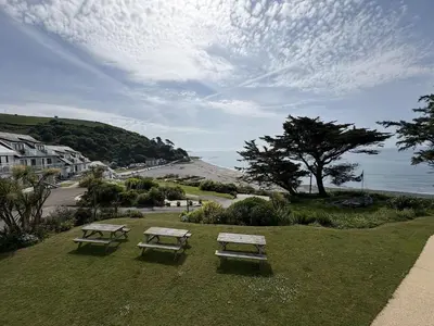 two picnic tables on a field with a view of the ocean at Sunrise Bay - Mount Brioni in Downderry