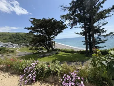 a view of a beach with flowers and trees at Trevian - Mount Brioni in Downderry