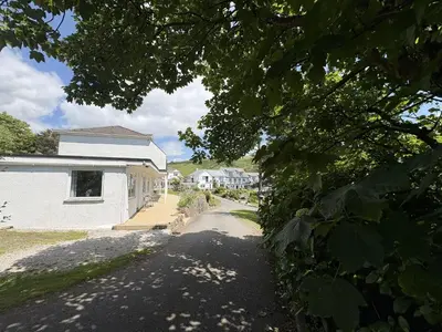 a street with a white house and a tree at Trevian - Mount Brioni in Downderry