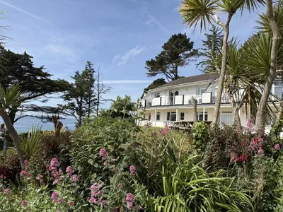 a white house with palm trees and flowers at Trevian - Mount Brioni in Downderry