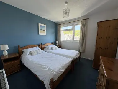 two beds in a bedroom with blue walls and a window at Ocean Waves - Mount Brioni in Downderry
