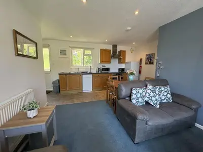a living room with a couch and a kitchen at Ocean Waves - Mount Brioni in Downderry