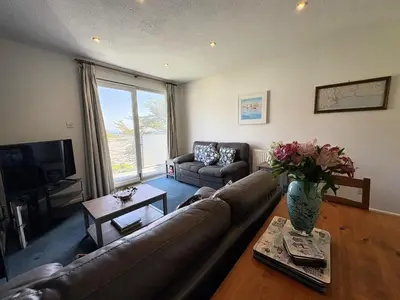 a living room with a couch and a vase of flowers at Ocean Waves - Mount Brioni in Downderry