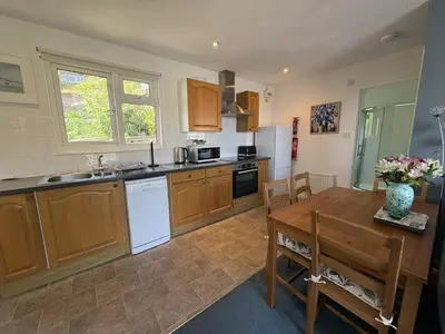 a kitchen with wooden cabinets and a wooden table with a tableablish at Ocean Waves - Mount Brioni in Downderry