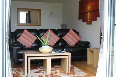 a black leather couch with a table in a living room at Ocean View - Mount Brioni in Downderry