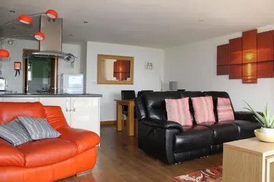 a living room with a leather couch and a kitchen at Ocean View - Mount Brioni in Downderry