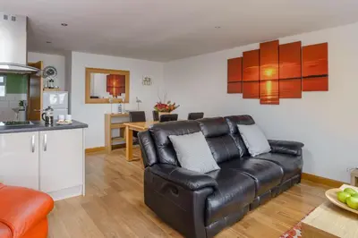 a living room with a leather couch and a kitchen at Ocean View - Mount Brioni in Downderry