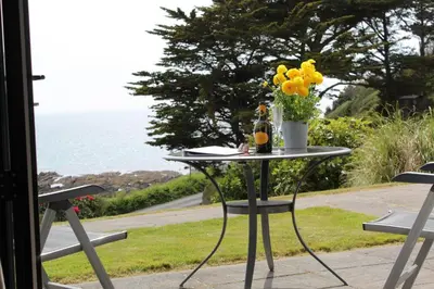 a table with a bottle of wine and flowers on it at Ocean View - Mount Brioni in Downderry