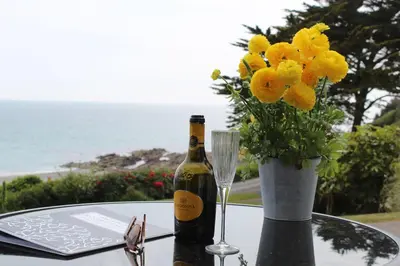 a bottle of wine and a vase of flowers on a table at Ocean View - Mount Brioni in Downderry