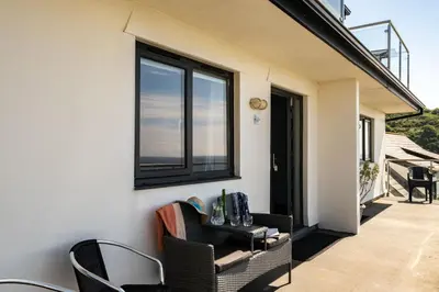 a patio with chairs and a table and a window at Sea Gem - Mount Brioni in Downderry