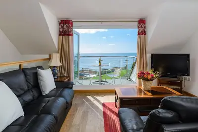 a living room with a couch and a view of the ocean at The Lookout - Mount Brioni in Downderry