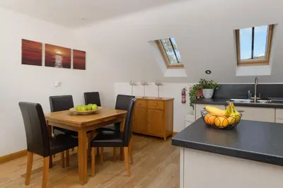 a kitchen with a wooden table and black chairs at The Lookout - Mount Brioni in Downderry