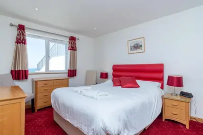 a bedroom with a large bed with a red headboard at The Lookout - Mount Brioni in Downderry