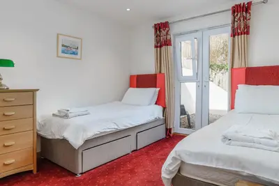 a bedroom with two beds and a dresser and a window at The Lookout - Mount Brioni in Downderry