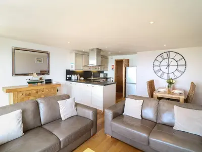 a living room with a couch and a kitchen at Sunset Surf - Mount Brioni in Downderry