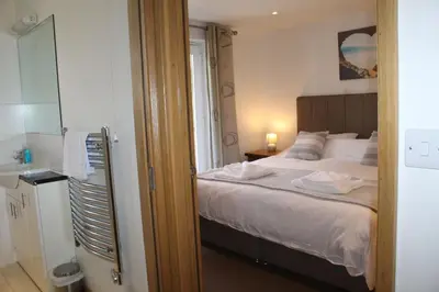 a bedroom with a bed and a bathroom with a sink at Sunset Surf - Mount Brioni in Downderry