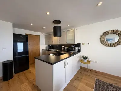 a kitchen with white cabinets and a black counter top at Mi Casa Su Casa - Mount Brioni in Downderry