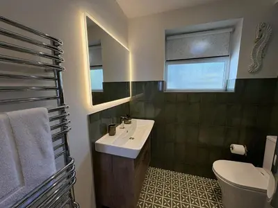 a bathroom with a sink and a toilet and a mirror at Mi Casa Su Casa - Mount Brioni in Downderry