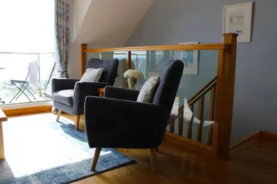 a living room with two chairs and a staircase at Seascape - Mount Brioni in Downderry